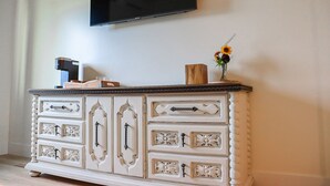 A white dresser with decorative handles and a flat-screen TV mounted above it. - The Wildflower Inn (Gold Beach)