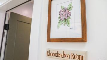 Ilustração botânica emoldurada e placa de madeira indicando um quarto chamado 'Rhododendron Room'.