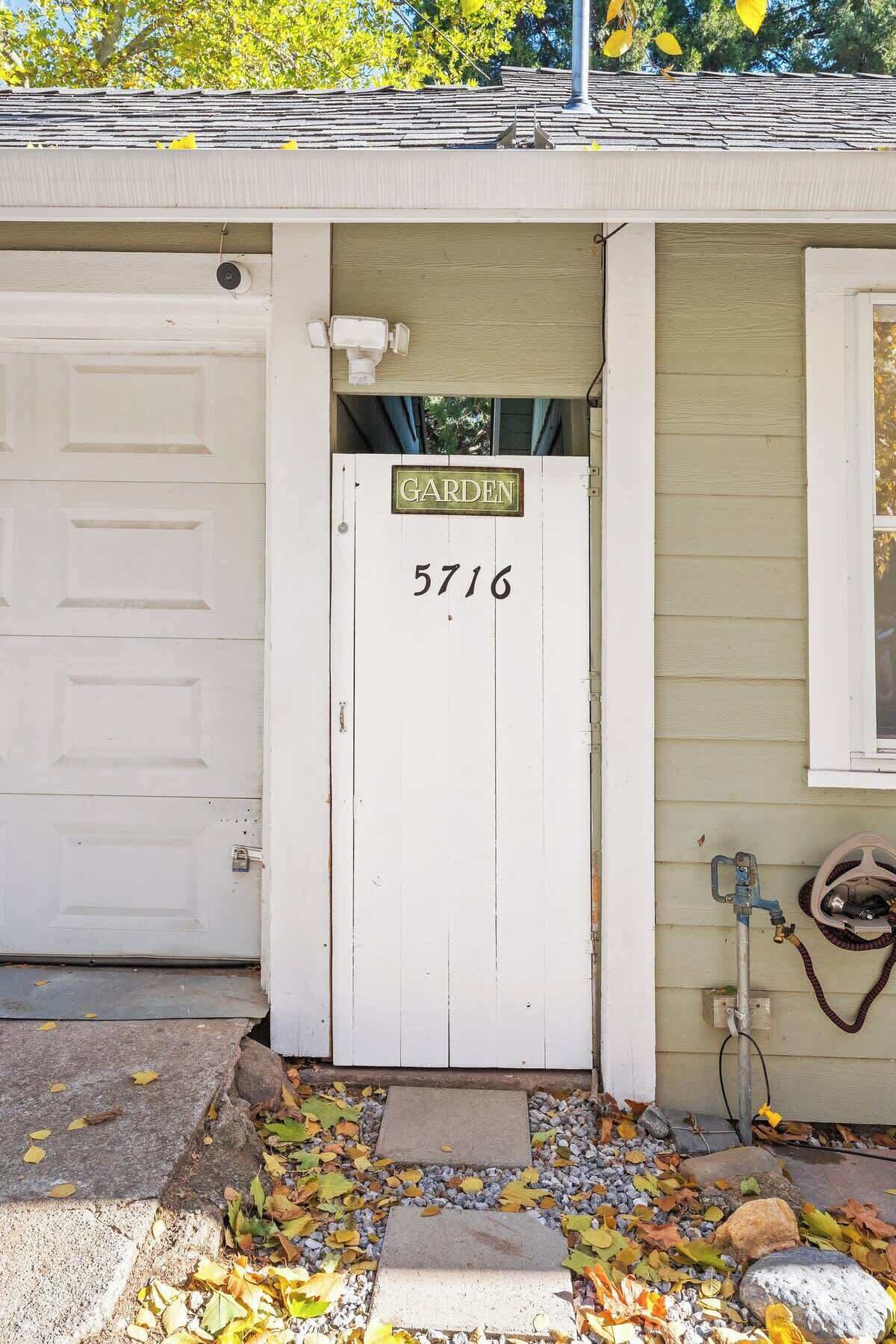 A white garage door with a 'GARDEN' sign and the number '5716' on a house.