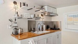 A modern kitchen with a wooden countertop, stainless steel appliances, and white cabinetry. - Picturesque Garden Retreat w/Deck With Hot Tub (Dunsmuir)