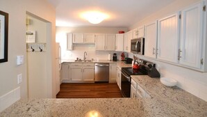 Una cocina moderna con armarios blancos, electrodomésticos de acero inoxidable y encimeras de granito.