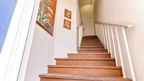 Een houten trap met witte leuningen, die uitkomt op een overloop.