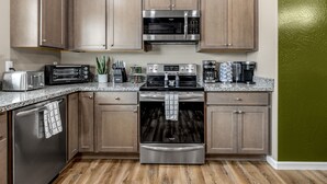 A modern kitchen with stainless steel appliances, wooden cabinets, and a granite countertop. - Lighthouse-Themed, Fastest WiFi, 2 King Beds Home (Medford)