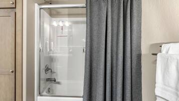 A bathroom with a shower, a glass door, and a towel rack with white towels.