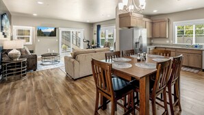 A spacious kitchen with wooden cabinets, a dining table with chairs, and a chandelier. - Lighthouse-Themed, Fastest WiFi, 2 King Beds Home (Medford)