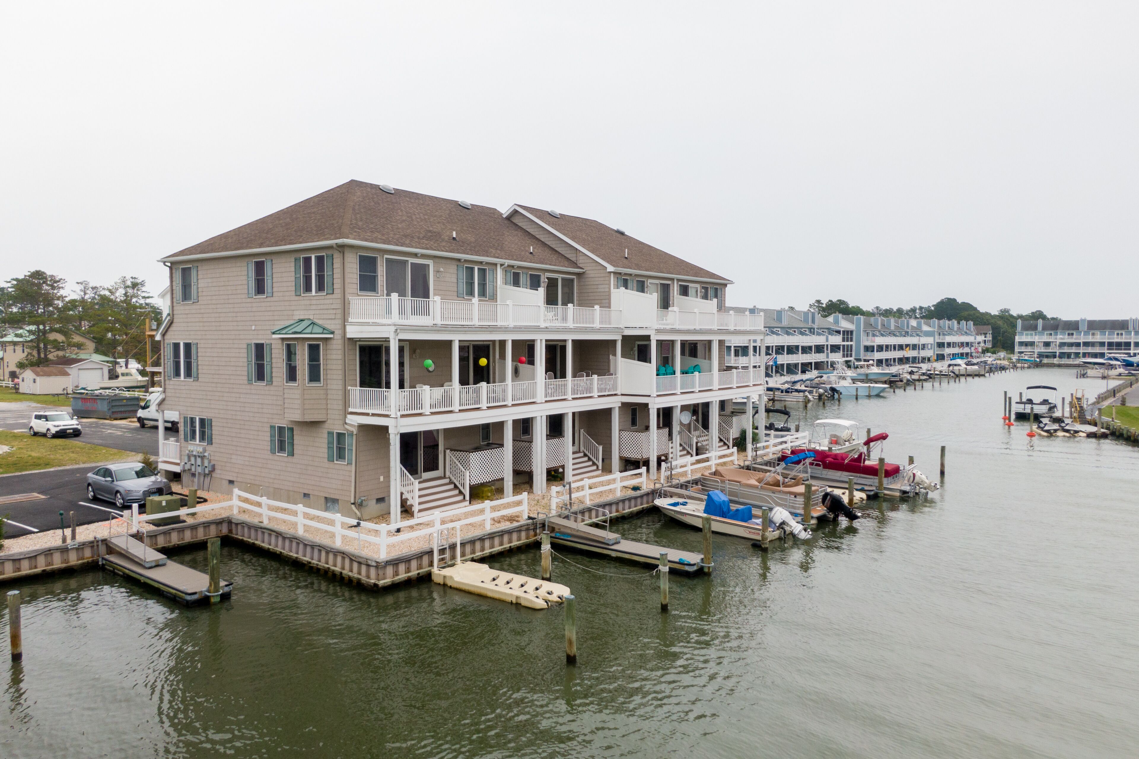 A multi-story waterfront building with balconies, a dock, and boats.