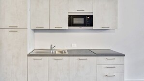 A modern kitchen with a built-in microwave, stainless steel sink, and light-colored cabinets.