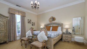A bedroom with a large bed, two chairs, a nightstand, a dresser, a mirror, and a chandelier. - Charming King Suite•Historic Mansion Near Monterey (Salinas)
