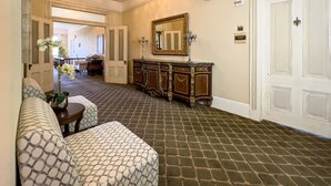 A hotel lobby with a patterned floor, a sofa, a mirror, and a cabinet. - Charming King Suite•Historic Mansion Near Monterey (Salinas)