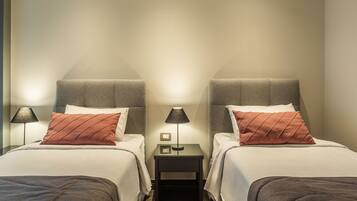 A twin room with two beds, a nightstand with a lamp, and a small table with a lamp.