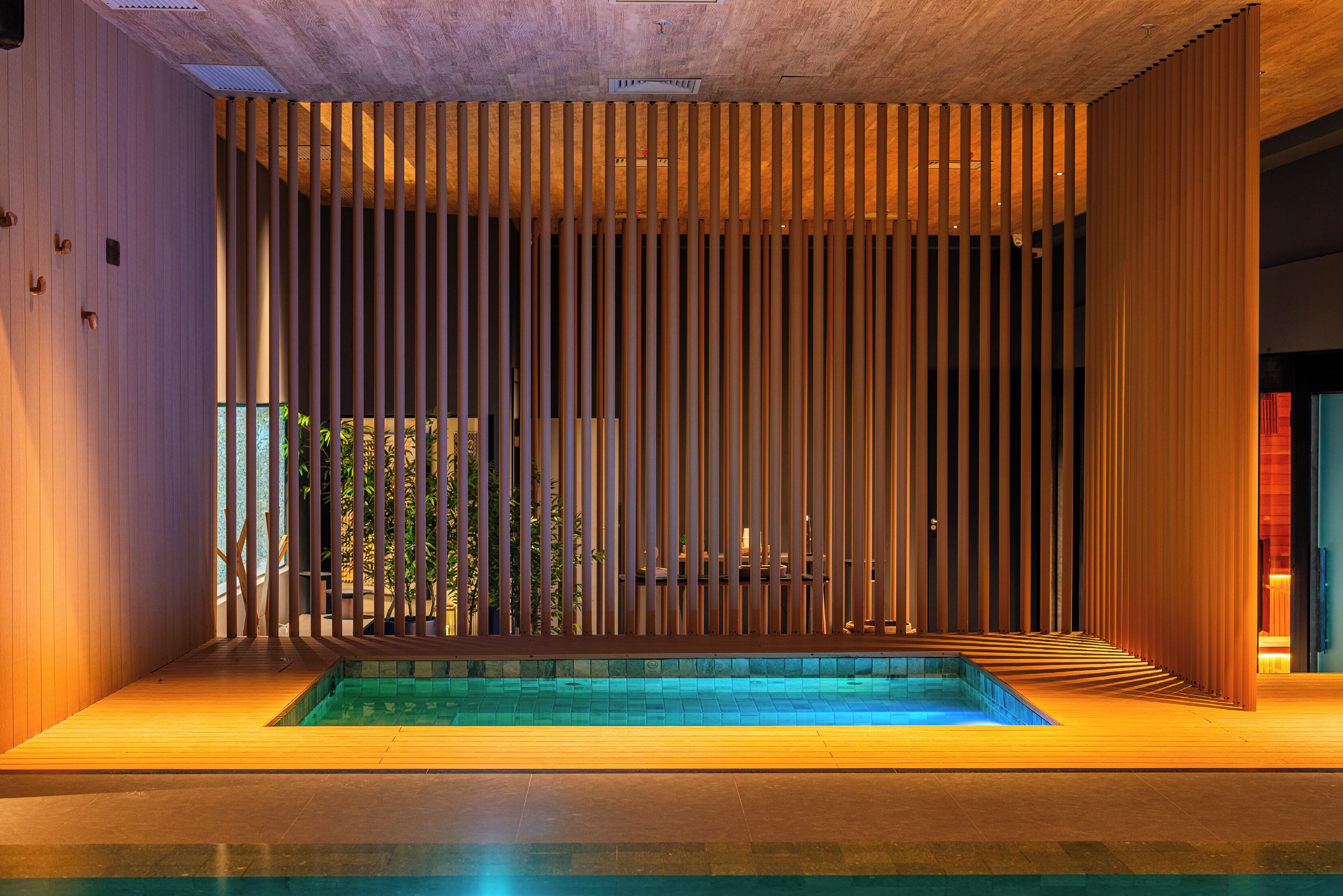 A modern interior with a pool, vertical wooden slats, and a concrete ceiling.