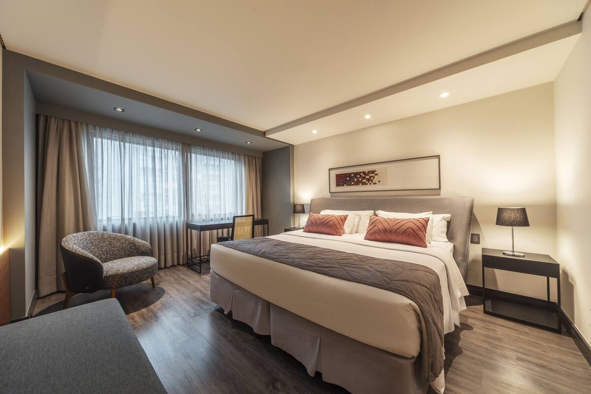 Une chambre d’hôtel moderne, dotée d’un grand lit, d’un bureau et d’une chaise.