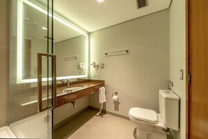 Un bagno moderno con cabina doccia in vetro, lavabo in marmo, WC e un ampio specchio.