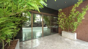Un vestíbulo moderno con puertas de vidrio, plantas de interior y un suelo pulido.