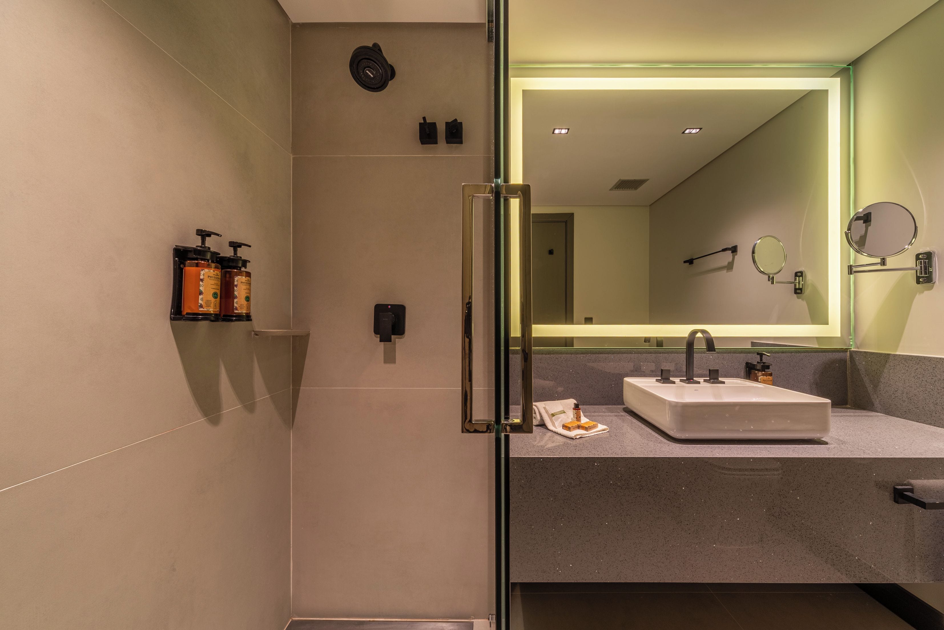 A modern bathroom with a glass shower enclosure, a vanity with a sink, and a large mirror.