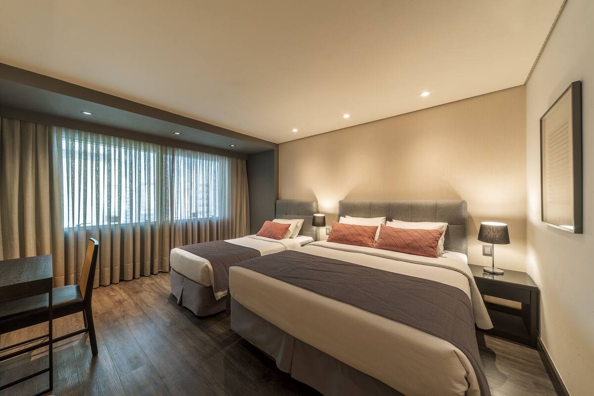 Une chambre d’hôtel moderne avec deux lits, un bureau et une chaise.