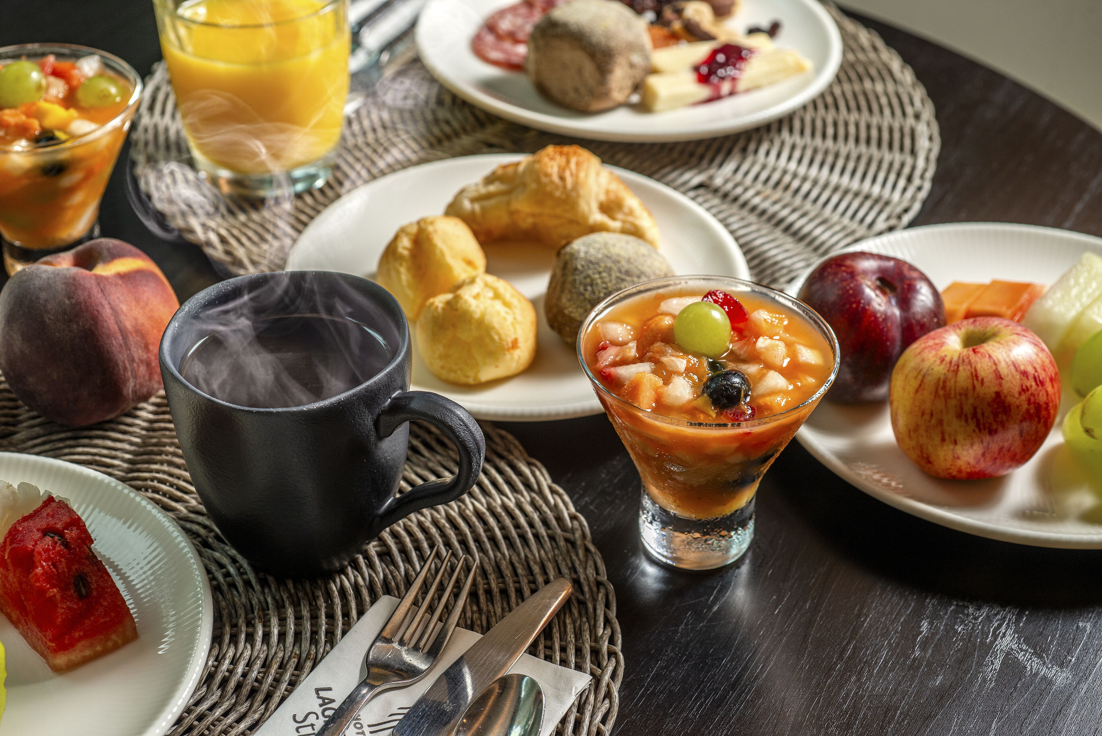 A breakfast setting with various dishes, a coffee cup, and a glass of juice.