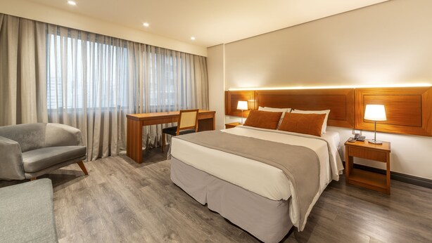 Een hotelkamer met een groot bed, een bureau, een stoel en een bank.