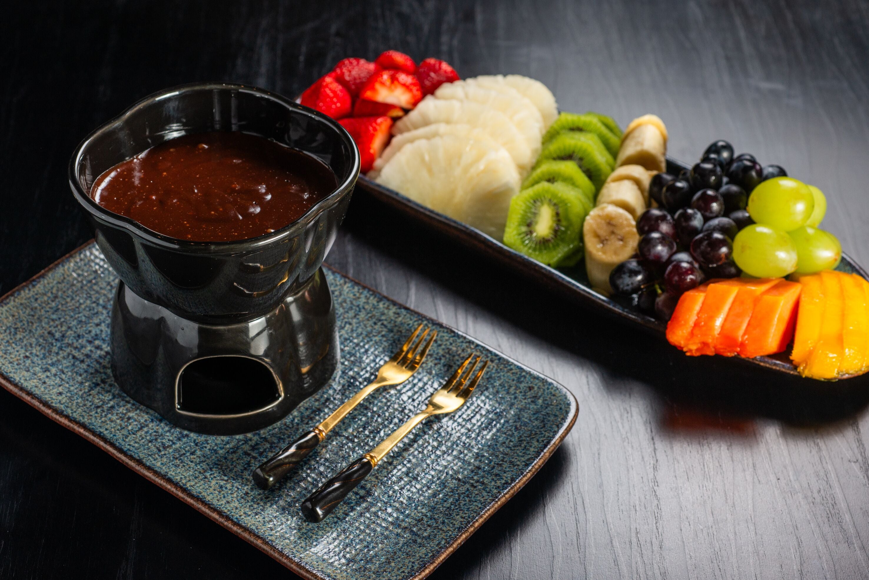 Un plato de postre con varias frutas y salsa de chocolate.
