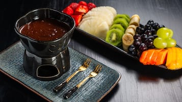 Un plato de postre con varias frutas y salsa de chocolate.