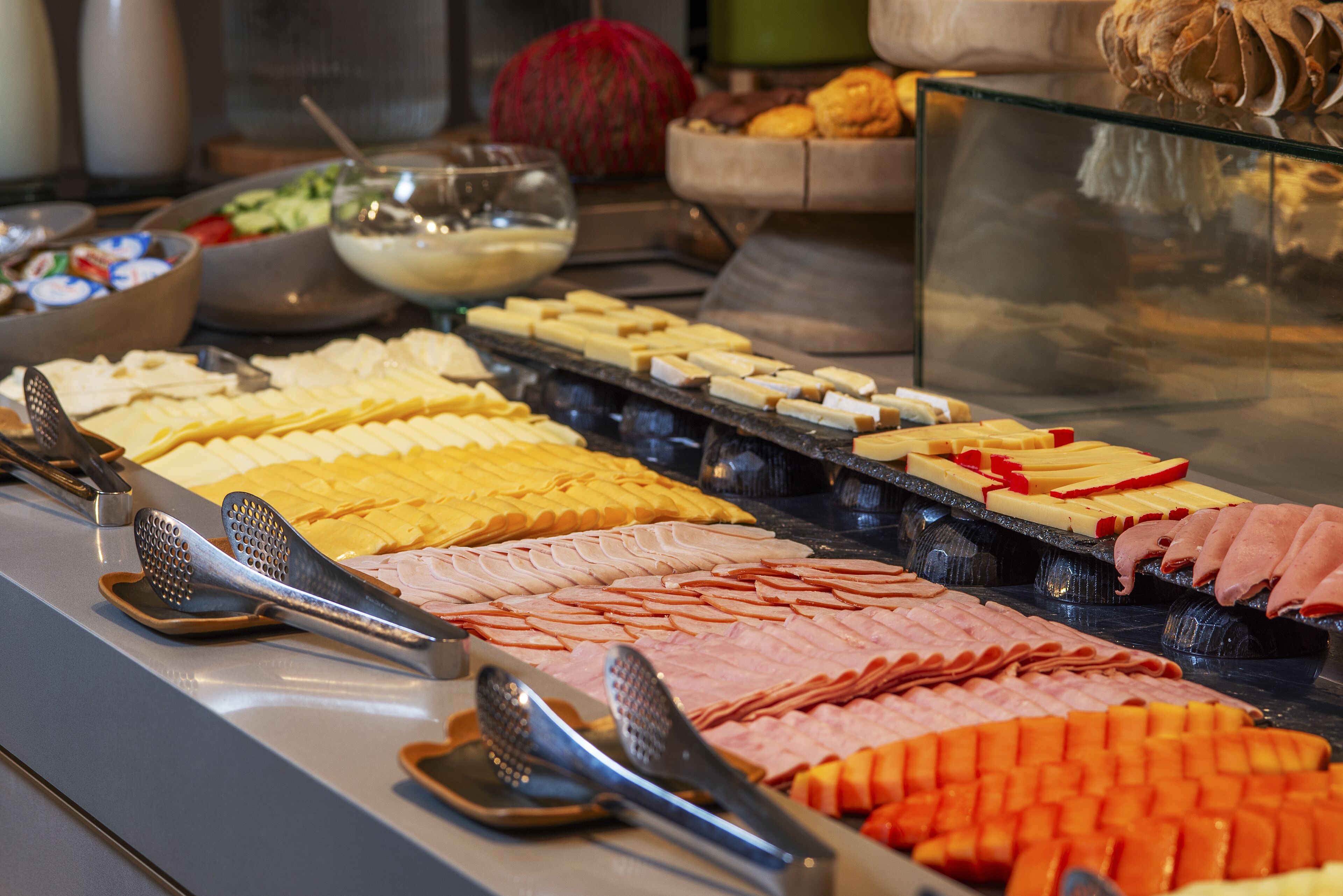Un buffet proposant une variété de plats, notamment des viandes, des fromages et des légumes.