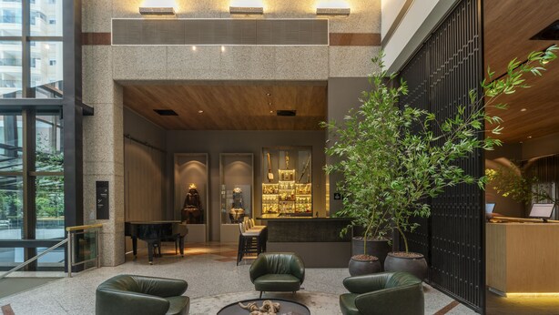 Un hall con un piano, zona de estar, mostrador de recepción y una planta grande en maceta.