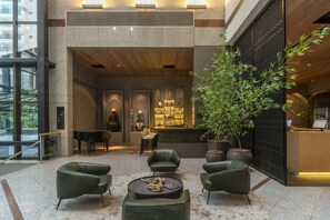 A lobby with a piano, seating area, reception desk, and a large potted plant. - Hotel Laghetto Stilo São Paulo (São Paulo)