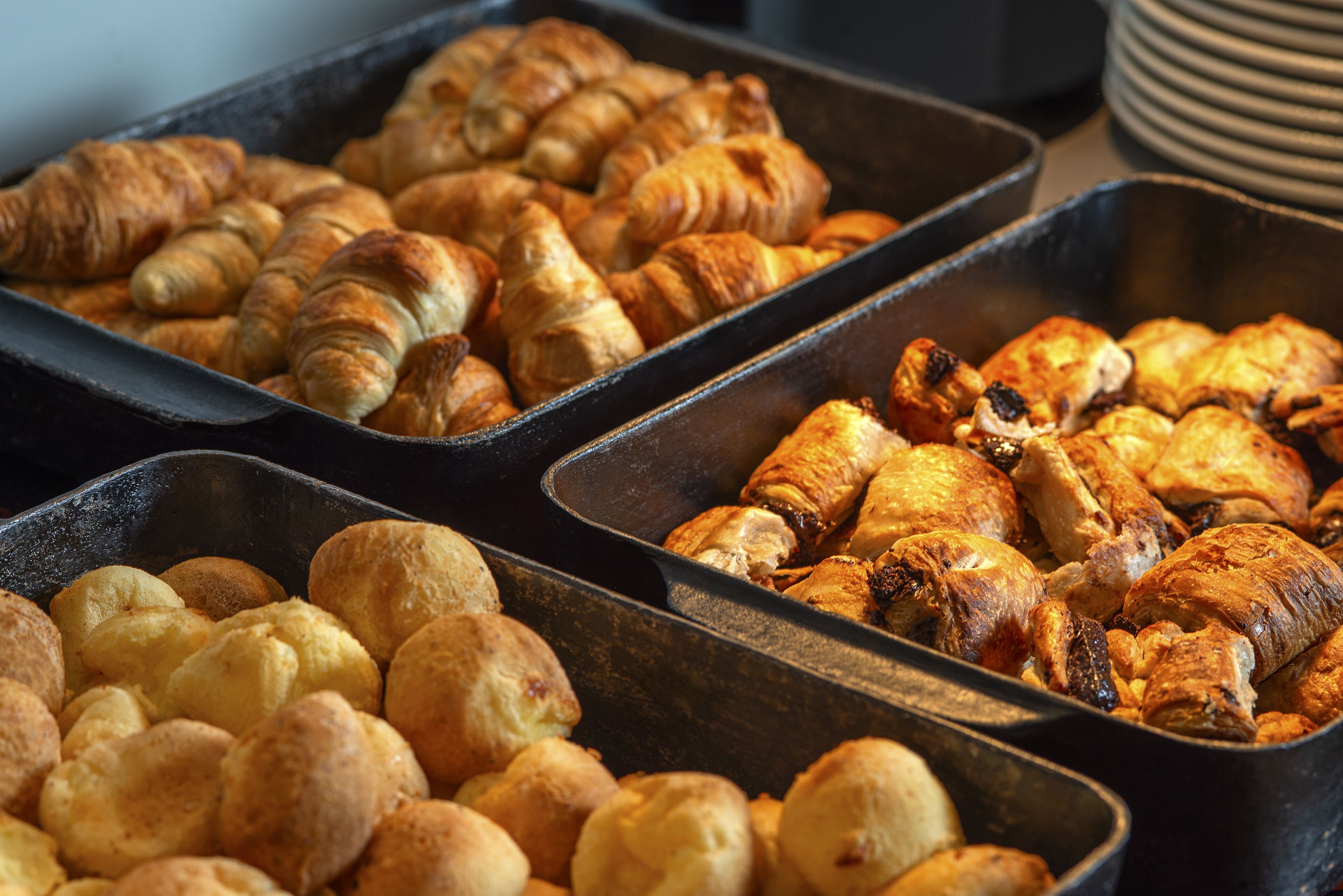 A variety of baked goods in trays, including croissants and bread rolls.