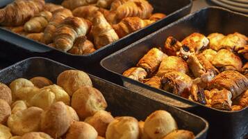 A variety of baked goods in trays, including croissants and bread rolls.
