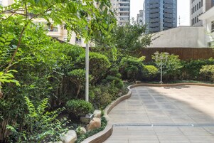 A landscaped pathway with greenery and a curved design, leading to a building entrance.