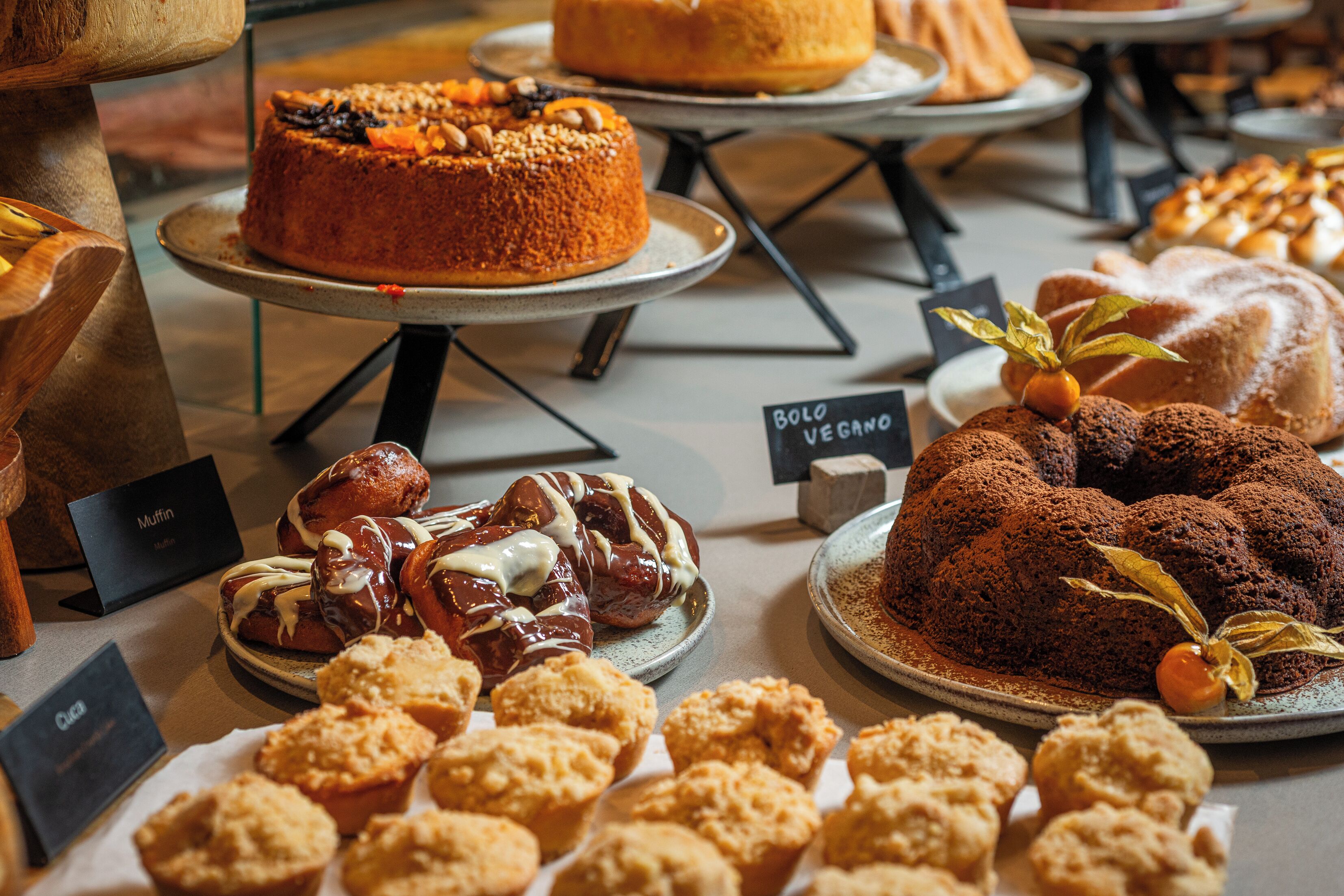 A variety of baked goods displayed on trays, including cakes, muffins, and cookies.