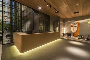 Un área de recepción moderna con un mostrador de madera, separador negro y muebles contemporáneos.