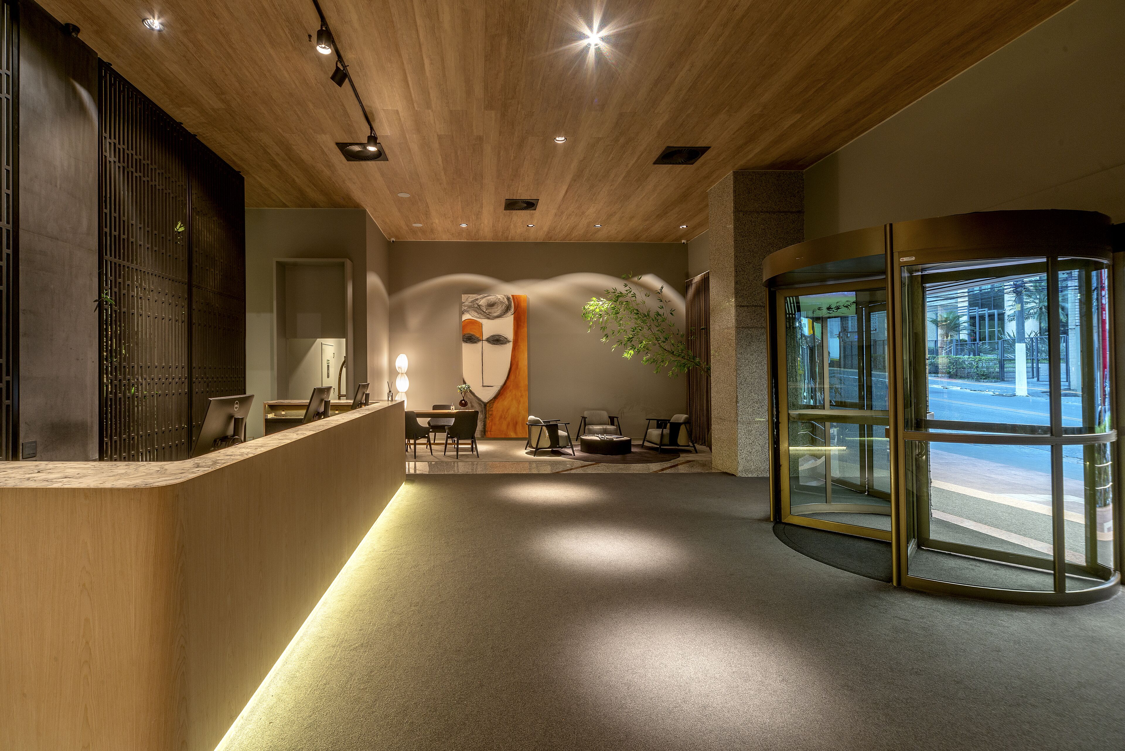 A reception area with a wooden reception desk, seating area, and a glass revolving door.