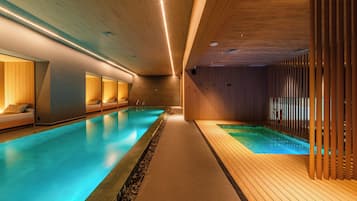 A modern indoor swimming pool with wooden paneling and a long corridor.