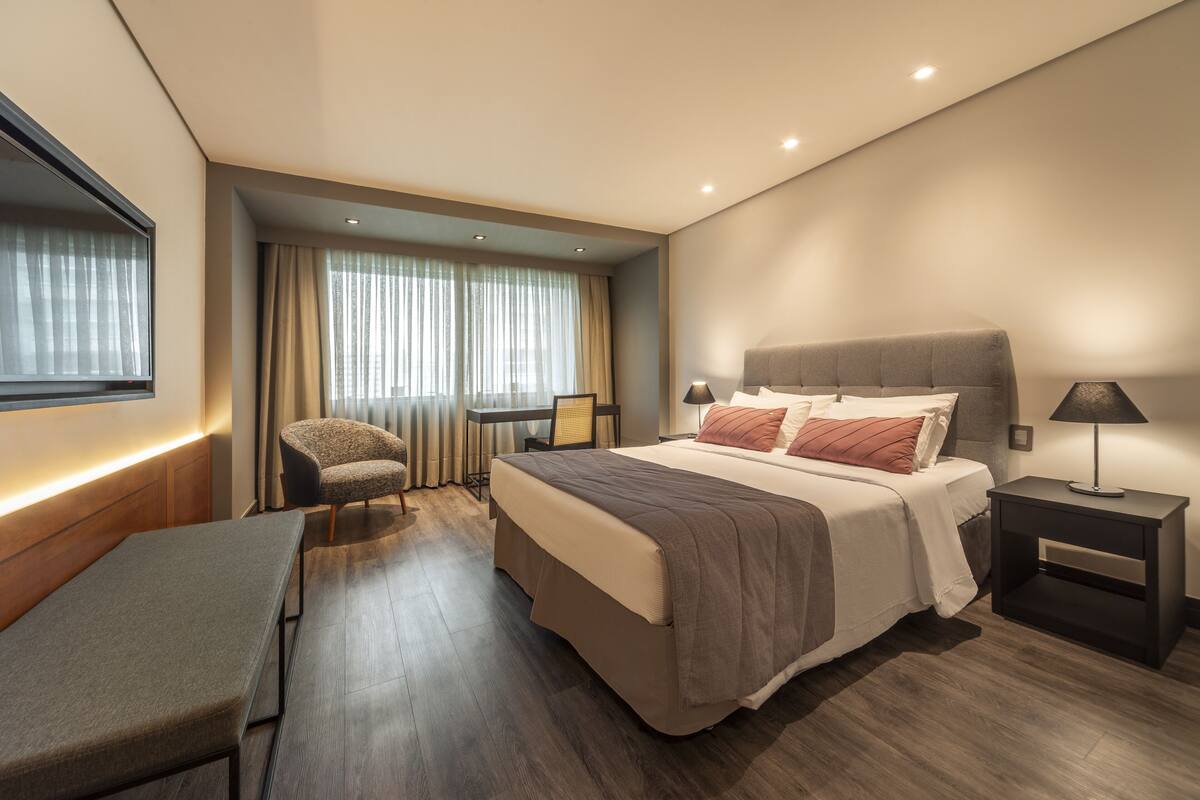 Une chambre d’hôtel moderne, dotée d’un grand lit, de tables de chevet, d’un bureau et d’une chaise.