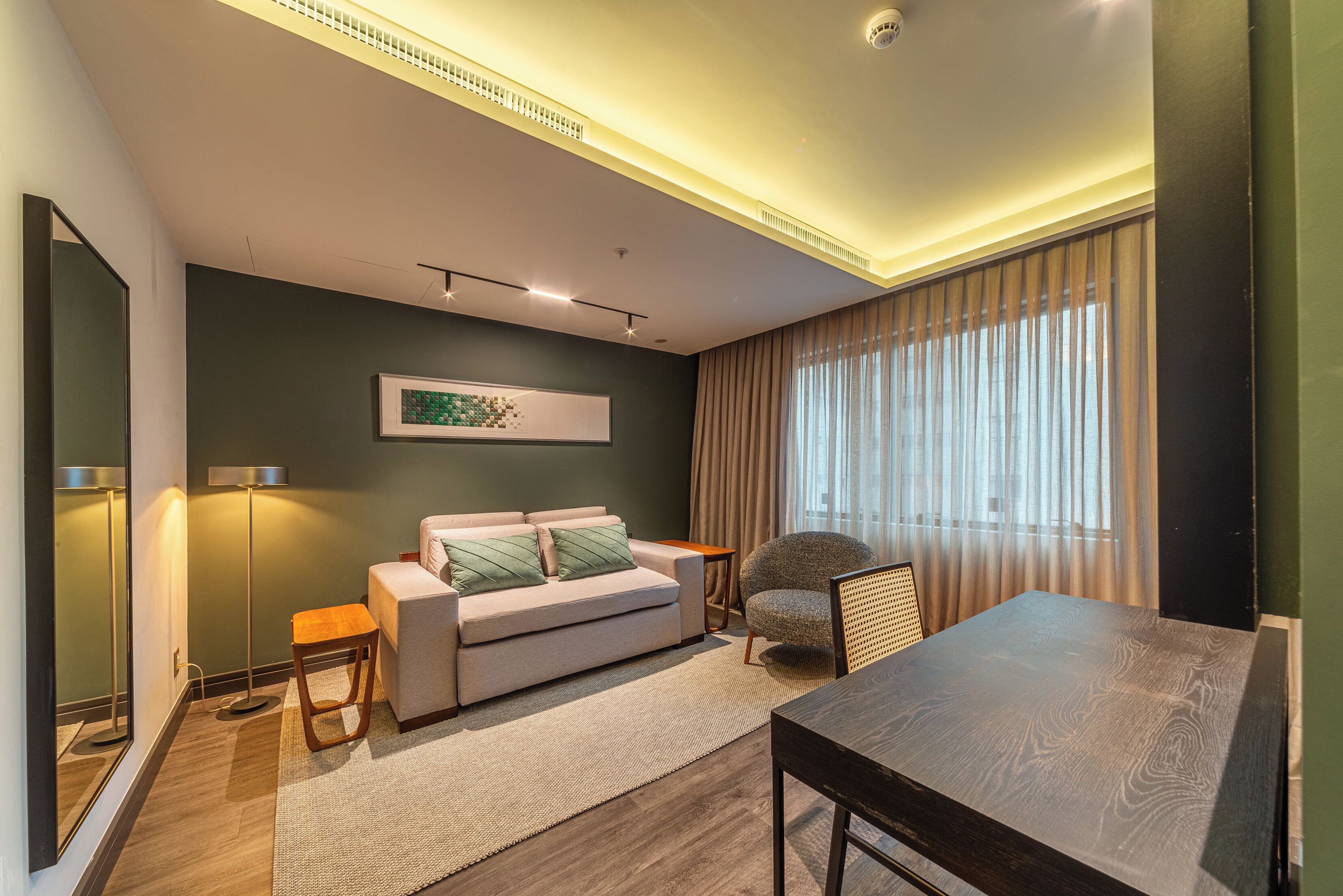 Uma sala de estar moderna com sofá, uma cadeira redonda, mesa de jantar e uma grande janela com cortinas.