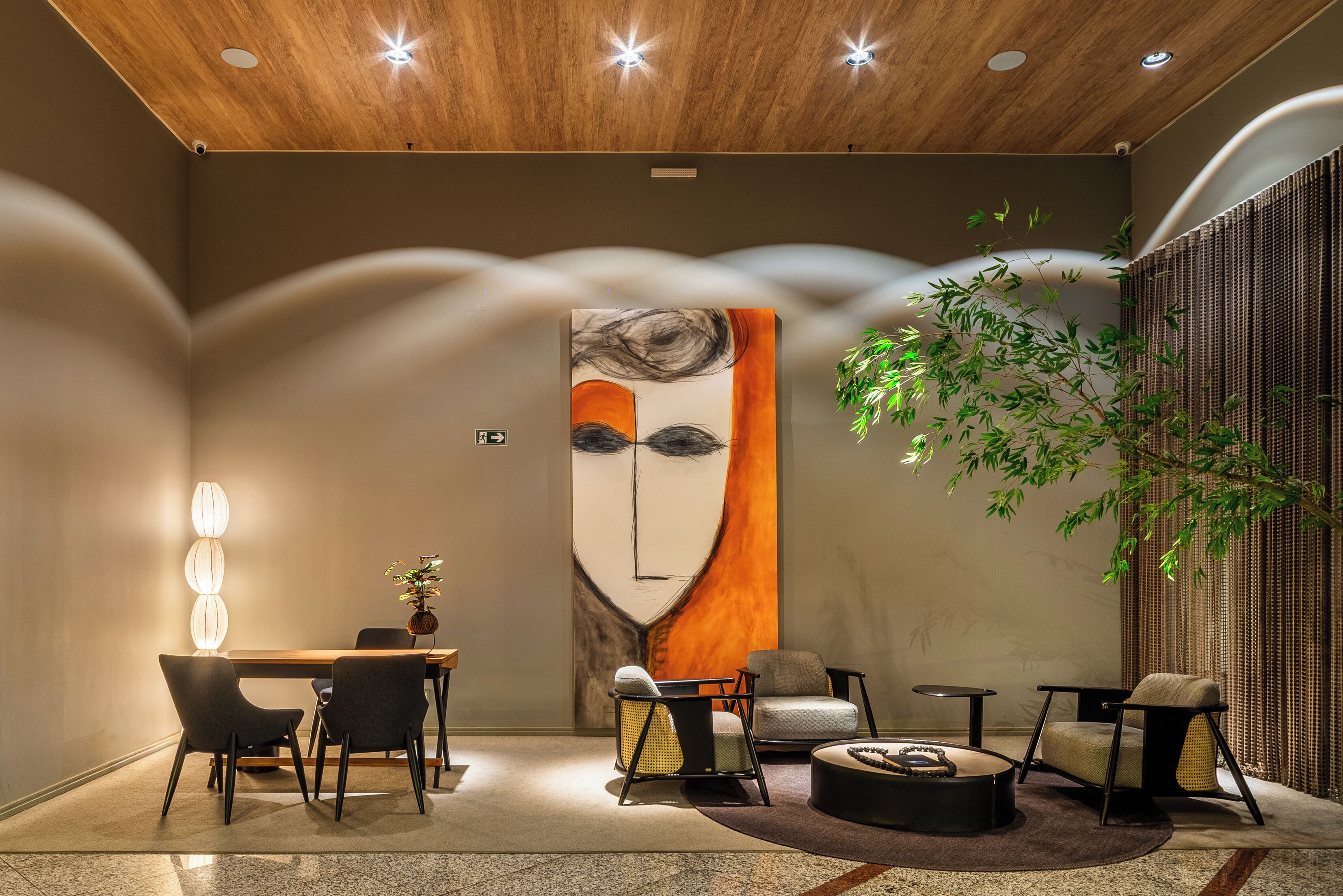 A modern interior with a dining area, seating, a large abstract painting, and a plant.