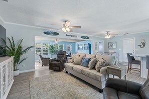 Relax in this inviting living area with a beige sofa, armchair, and chair, surrounded by a light blue accent wall and a potted plant.