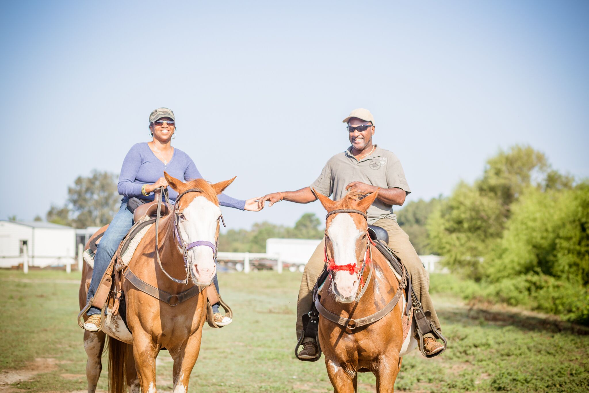 Two people riding horses in an open field with a clear sky.