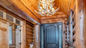 A log cabin interior with a wooden ceiling, a dark wooden door, and a stone-tiled floor. - One-of-A-Kind Log Home in the Heart of the White Mountains NH (Intervale)