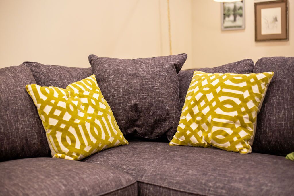 A gray sofa with two patterned pillows.