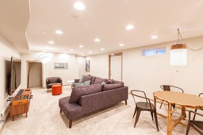 Un vaste espace de vie comprenant un canapé, un pouf et une table à manger avec des chaises.