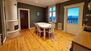 A dining area with a white table and chairs, a kitchen area with a coffee machine, and a view through a window. - Historic Villa in the heart of Gränna (Jönköpings län)