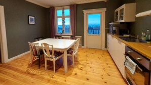 A compact kitchen with a dining area, wooden flooring, and a view through a window. - Historic Villa in the heart of Gränna (Jönköpings län)