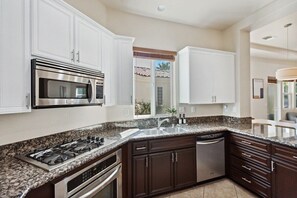 Eine moderne Küche mit Granit-Arbeitsplatten, Edelstahlgeräten und dunklen Holzschränken.