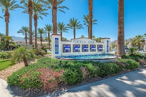 A sign for Puerta Azul with a fountain, surrounded by palm trees and a landscaped garden. - Exclusive Resort Haven | Private Pool Tennis & Spa (La Quinta)