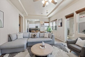 A modern living room with a sectional sofa, a round coffee table, and a ceiling fan. - Exclusive Resort Haven | Private Pool Tennis & Spa (La Quinta)