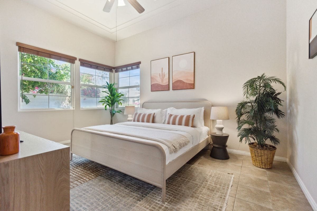 A bedroom with a bed, bedside tables, a window, and a plant.
