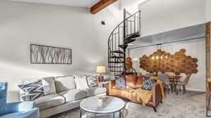 A modern living room with a sofa, coffee table, and a spiral staircase. - Breck-Ski IN Condo⛷Main Street 🏔 Views 😴 sleeps 8! $0 Cleaning fee (Breckenridge)