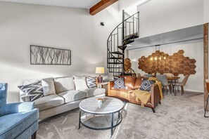 Un salon moderne avec un canapé, une table basse et un escalier en colimaçon.
